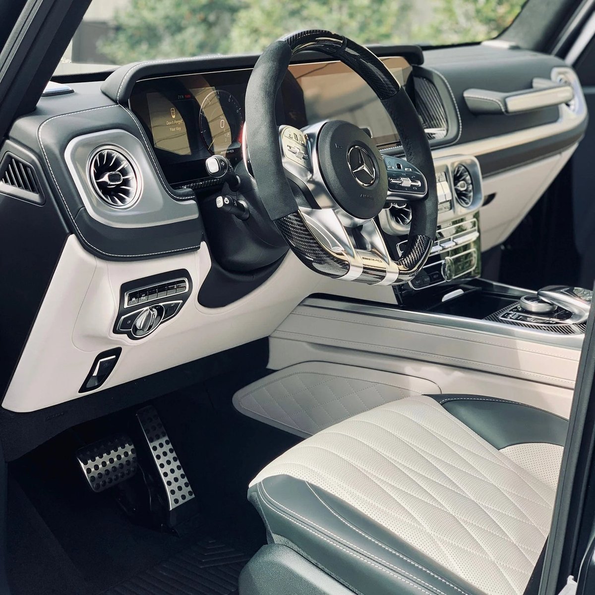 Luxury car interior with black leather steering wheel, white and black leather seats, and modern dashboard with circular air vents